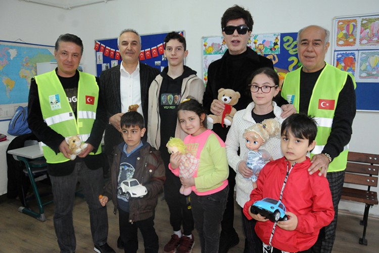 Oyuncak dağıtıp okul bahçesinde şarkı söyledi